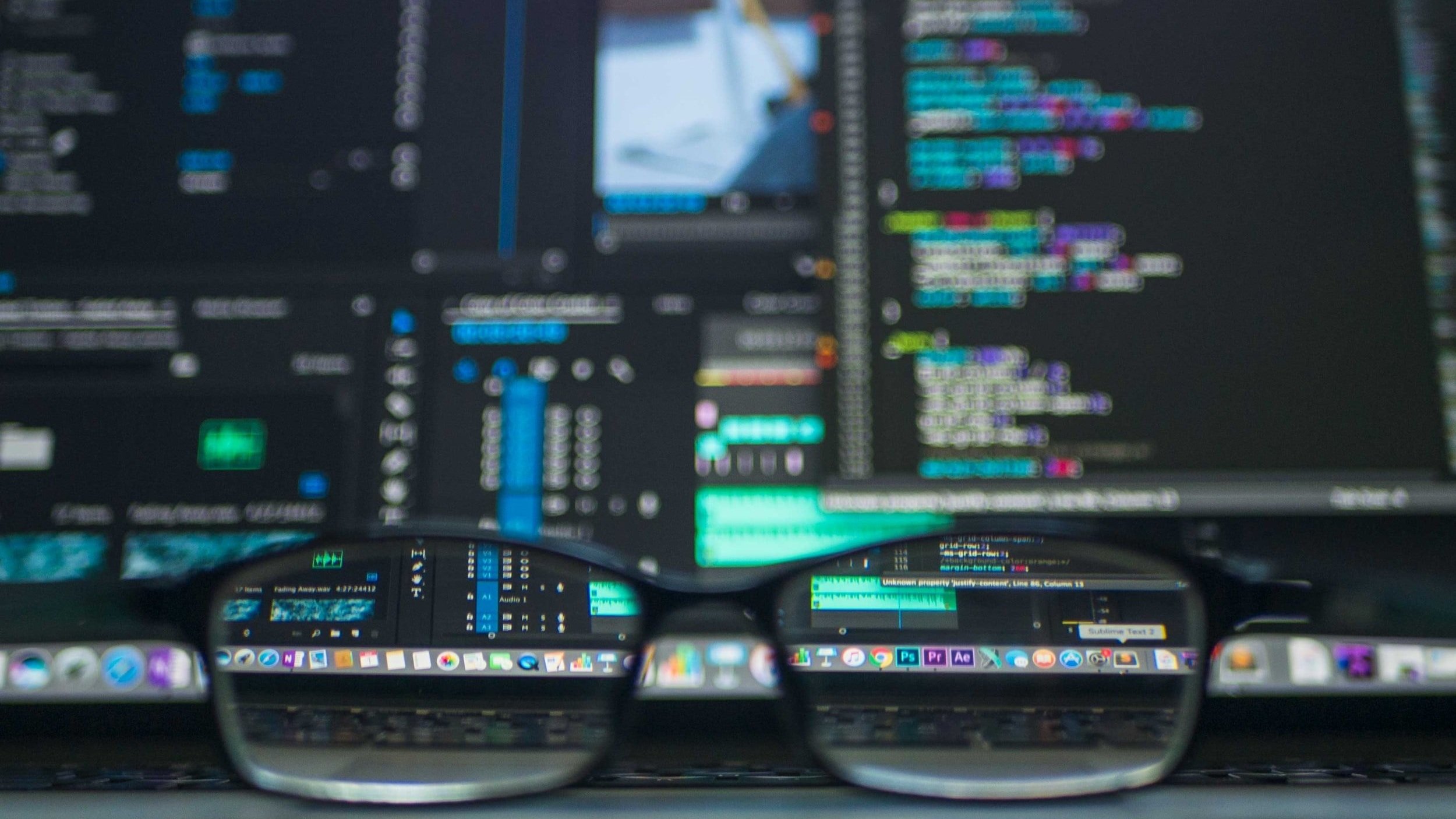 Eyeglasses in front of monitors displaying code